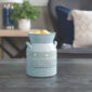 Bring cozy charm to your home with the Blue Blessed Illumination Warmer, designed to look like a vintage milk jug. Featuring a soft matte blue finish with golden flecks, ridged stripe accents, and raised “Blessed” lettering, this ceramic fragrance warmer blends seamlessly into farmhouse, cottagecore, or rustic décor styles.