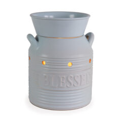 Bring cozy charm to your home with the Blue Blessed Illumination Warmer, designed to look like a vintage milk jug. Featuring a soft matte blue finish with golden flecks, ridged stripe accents, and raised “Blessed” lettering, this ceramic fragrance warmer blends seamlessly into farmhouse, cottagecore, or rustic décor styles.
